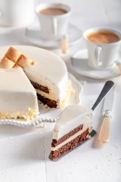 Delicious white chocolate cake with brownie, glaze and white chocolate. White chocolate cake on white porcelain.