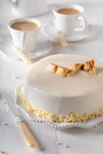 Luxury white chocolate cake with gold chocolate and glaze. White chocolate cake on white porcelain.