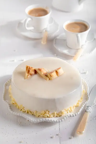 Luxury white chocolate cake with brownie, glaze and white chocolate. White chocolate cake on white porcelain.