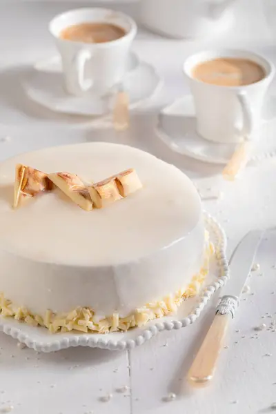 Delicious white chocolate cake with gold chocolate and glaze. White chocolate cake on white porcelain.