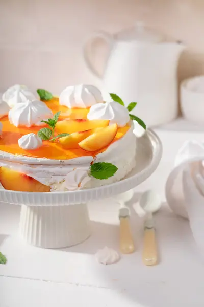 Tasty peach meringue with powdered sugar and fruits. Peach meringue made of fruits and cream.
