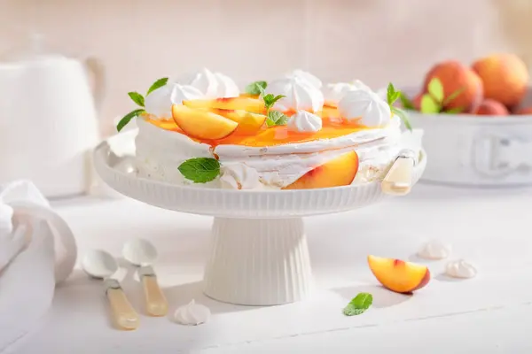 Sweet peach meringue with powdered sugar and fruits. Peach meringue made of fruits and cream.