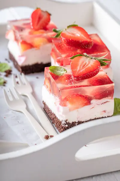 Delicious jelly cake with strawberries with fluffy cream layer. Cake with jelly on top.