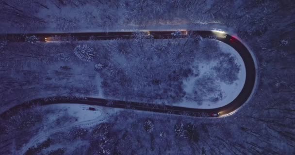 冬の滑りやすい巻線道路のヘッドライト付きの車を運転する 道路に黒いアイス 夜間の冬の輸送 — ストック動画