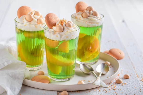 Sweet green jelly served with biscuits and sprinkles. Green jelly with peaches and biscuits.