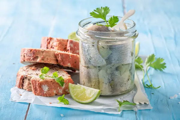 Fresh and delicious marinated herring as source of omega fat. Fish in jar served with bread.