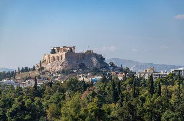 A picture of the Acropolis of Athens, and the Parthenon, as seen above a tree line in the foreground.
