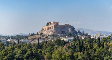 A picture of the Acropolis of Athens, and the Parthenon, as seen above a tree line in the foreground.