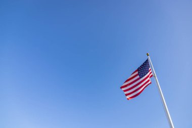Mavi gökyüzünün altında bir Amerikan bayrağının resmi..