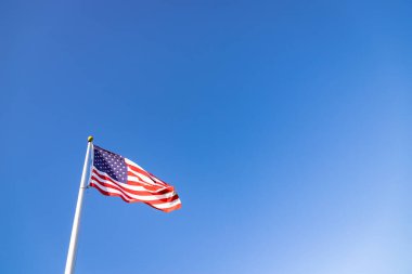 Mavi gökyüzünün altında bir Amerikan bayrağının resmi..