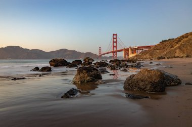 Gün batımında Golden Gate Köprüsü ve Baker Sahili 'nin bir resmi..