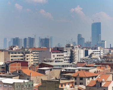 Uzaktaki modern binalarla İzmir 'in merkezindeki çatıların resmi.