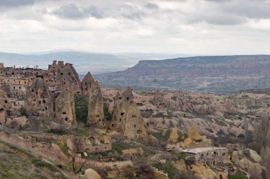 Arka planda Goreme Tarihi Ulusal Parkı ve önplanda Uchisar Kasabası 'nın bulutlu bir günde çekilmiş bir fotoğrafı..
