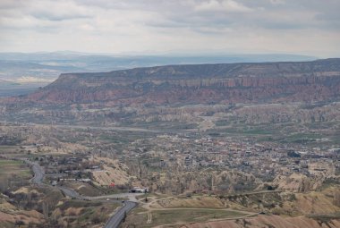 Bulutlu bir günde Goreme Tarihi Ulusal Parkı ve Goreme Kasabası 'nın resmi..