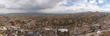 Arka planda Goreme Tarihi Ulusal Parkı ve önplanda Uchisar Kasabası 'nın bulutlu bir günde çekilmiş bir panorama resmi..