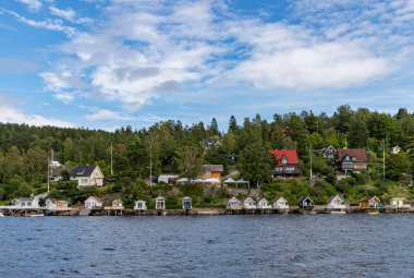 Oslofjord 'daki birden fazla evin ve küçük kulübelerin resmi..