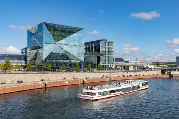 stock image A picture of the 3XN Cube Berlin building, the Berlin Central Station behind it, and a cruise on the Spree river.