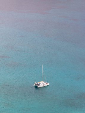 A picture of a sailing catamaran surrounded by blue water.