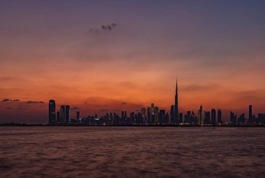 Gün batımında Dubai şehir merkezinin renkli bir resmi, Burj Halife diğer gökdelenlerde yükseliyor..