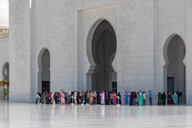 A picture of the Sahan Courtyard of the Sheikh Zayed Grand Mosque with a large crowd of visitors near the entrance.
