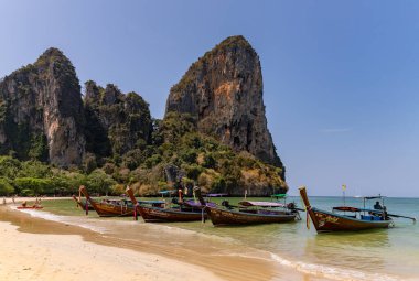 Batı Railay Sahili 'nin renkli uzun kuyruklu teknelerinin kıyıda dinlendiği bir resmi..