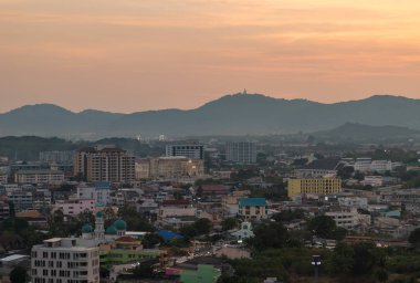 Gün batımında Güneybatı Phuket 'in bir resmi, Büyük Buda heykeli uzak merkezde, tepelerin üstünde görünür..