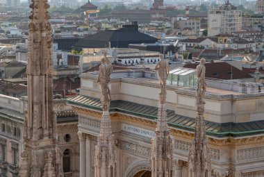 Duomo di Milano ya da Milan Katedrali 'nin çatı kulesi ve Galleria Vittorio Emanuele II' nin çatısına bakan heykeli..