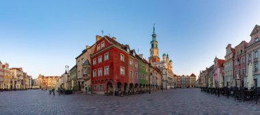 Poznan Eski Pazar Meydanı 'nın güneş doğarken çekilmiş bir panorama resmi. Belediye binası, renkli Ticaret Evleri ve sergilenen kiralık evler..