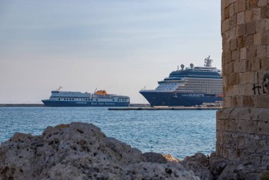 Büyük bir gemi seyahatinin ve Rhodes Limanı 'na yanaşmış küçük bir feribotun resmi..