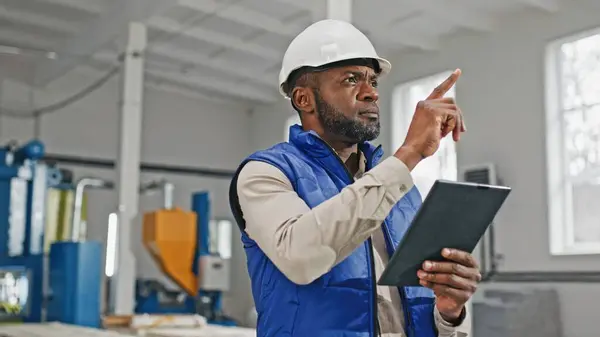 Close-up of tall good-looking bearded African-American male measuring comparing and looking in his gadget. Serious worker moving his head counting and distributing updated information.