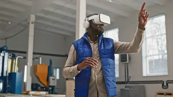 Close-up portrait of nice employed busy bearded African-American male during interesting work process. Innovative original worker using contemporary latest up-to-date VR device.