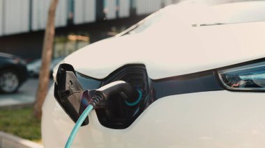 Dışarıdaki elektrikli arabasını şarj etmek için kablo kullanan adamı yakından çek. Erkek olan şarj kablosunu caddedeki şarj limanına bağlıyor. EV teknoloji konsepti. Gelecekteki otomobil şarj istasyonu