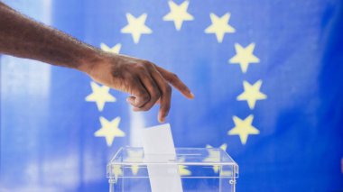 Avrupa Seçim Süreci 'nin ön görüşü. İnsanlar oy pusulasını şeffaf sandığa koyuyor. Arka planda büyük bir Avrupa Birliği bayrağı var. Parlamento adaylarını seçen vatandaşlar. Oylama konsepti.
