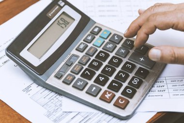 Bir iş adamının elini hesap makinesi ve belgelerle kapatın.