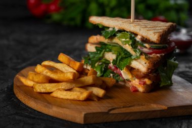 Domuz pastırmalı ve ahşap tahtada yeşillikli sandviçlerin yakın plan çekimi.