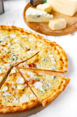 Tahta üzerinde dört peynirli pizza ve beyaz ahşap bir masada İtalyan pizzası için taze malzemeler. .