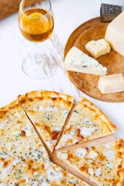 Tahta üzerinde dört peynirli pizza ve beyaz ahşap bir masada İtalyan pizzası için taze malzemeler. .