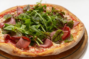 Beyaz arka planda jambonlu ve fesleğenli pizza.