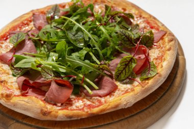 Beyaz arka planda jambonlu ve fesleğenli pizza.