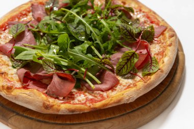 Beyaz arka planda jambonlu ve fesleğenli pizza.