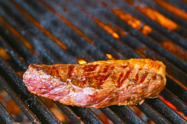 Izgarada alevler içinde biftek cızırdıyor.