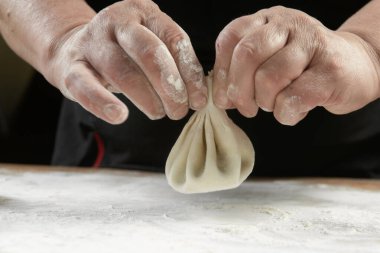 Aşçı ahşap masada khinkali yapıyor. İşlem hazırlığı Gürcistan yemeği. yiyecek konsepti.