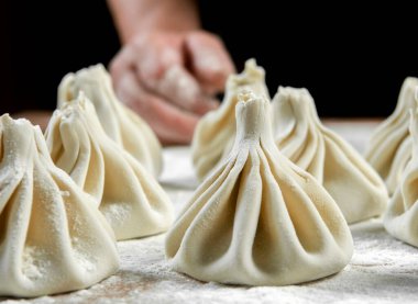 Aşçı ahşap masada khinkali yapıyor. İşlem hazırlığı Gürcistan yemeği. yiyecek konsepti.