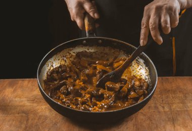 Aşçı eti sebzeli ve soğanlı bir kasede hazırlar. Doğu mutfağı.