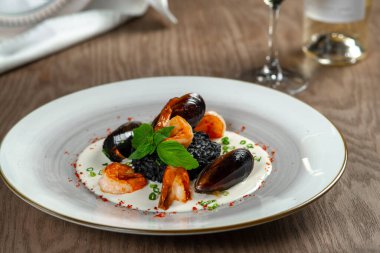 Beyaz bir tabakta deniz ürünleri, midyeler ve karidesler.