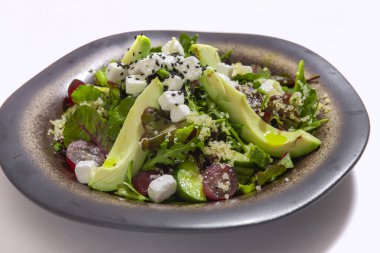 Bowl of vegetables salad with avocado on white background