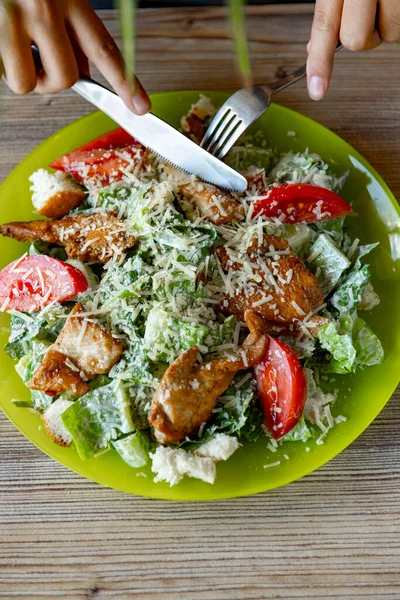 Woman eating salad with grilled chicken breast with vegetables and herbs . Caesar salad