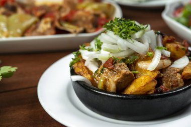 Beef stew with potatoes, carrots and herbs on black background with copy