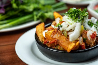 Beef stew with potatoes, carrots and herbs on black background with copy