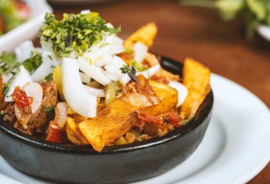 Beef stew with potatoes, carrots and herbs on black background with copy